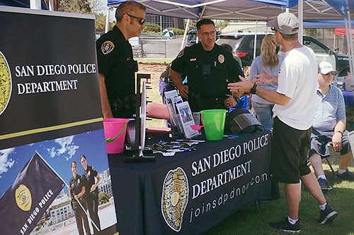 Two police officers speaking to a candidate at a recruiting event